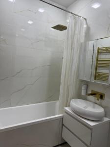 a white bathroom with a sink and a shower at Апартаменты в центре Худжанда in Khujand +11 photos
