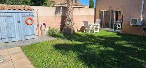 a backyard with a blue door and a table and a tree at Tranquillo avec piscine privée in Istres