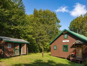 a couple of barns in a field with trees at Moose Point Cabin in Greenville
