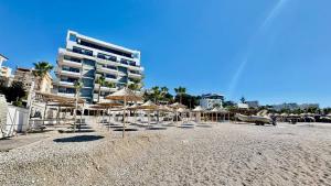 a beach with chairs and umbrellas and a building at 4 Seasons Sea View Apartment in Sarandë