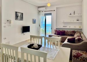 a living room with a couch and a table and chairs at 4 Seasons Sea View Apartment in Sarandë