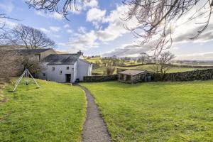 una casa in mezzo a un campo con un sentiero di Drawell Cottage - Situated on a working farm a Sedbergh
