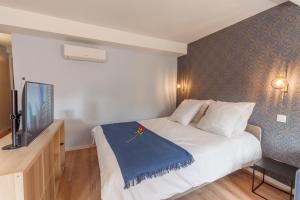 Una habitación de hotel con una cama y un televisor de pantalla plana. en Daumas 4 - Charme & Elégance, en Toulon
