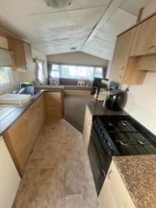 a small kitchen with a stove and a counter top at 3 Bed Caravan - Sleeps 8 - Pets - Parking - Wifi in Rhyl +6 photos