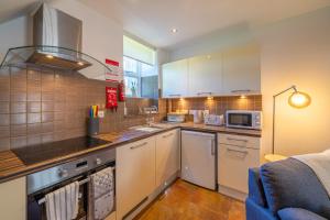 a kitchen with white cabinets and a stove top oven at Bell Cottage - Cockermouth is five minutes walk to pubs, restaurants and shops in Cockermouth