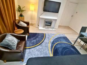 ein Wohnzimmer mit zwei Stühlen und einem Fernseher in der Unterkunft Modern Penge East Apartment in Sydenham