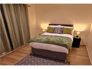 Schlafzimmer mit einem Bett mit grünen und weißen Kissen in der Unterkunft Modern Penge East Apartment in Sydenham