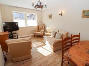 een woonkamer met een bank en een tafel bij Catkin Cottage in Wooler