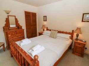 een slaapkamer met een groot houten bed met witte lakens bij Catkin Cottage in Wooler +45 foto's