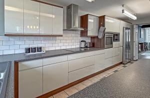 a kitchen with white cabinets and stainless steel appliances at SPACIOUS STYLISH HOME, Foosball Table, FREE PARKING, Driveway, Garden & LAUNDRY ROOM, 2 DOUBLE BEDROOMS & LED Media wall in Luton