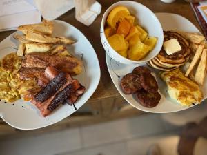 two plates of breakfast foods and a bowl of fruit at Accra Luxury Apartments At The Sanga Estates in Accra +9 photos