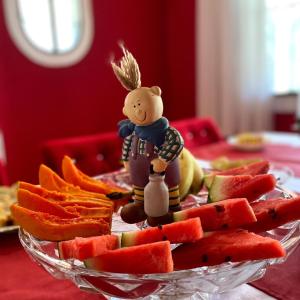 a glass bowl of watermelon and a figurine of a man and a woman at Casarão imperador in Guapimirim