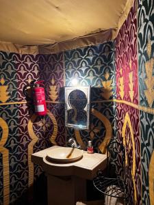 a bathroom with a sink and colorful wallpaper at Nomada Desert Camp in Merzouga +133 photos