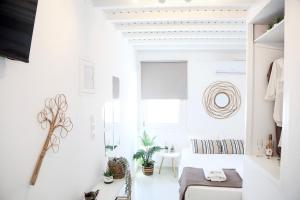 a white room with a bed and a window at Heart of the City Studios in Mikonos