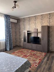 Un dormitorio con una cama y un televisor de pantalla plana. en Гостевой Дом, en Kooperator