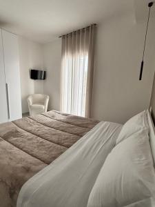 a white bedroom with a bed and a window at A casuzza in Modica