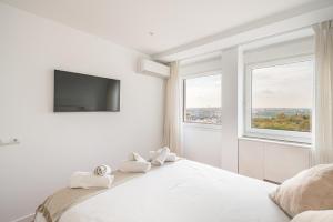 a white bedroom with a large bed with a flat screen tv at Plaza España Superb Views in Madrid