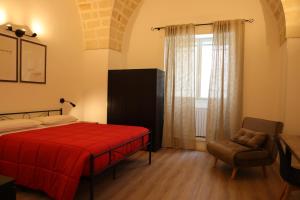 a bedroom with a red bed and a chair and a window at Casa Giudea in Brindisi