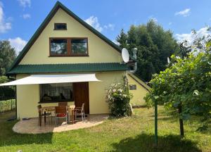 a small yellow house with a table and chairs at Dom Gaja in Ińsko