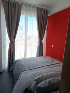 a bedroom with a bed with a red wall and a window at House on the Top in Patra