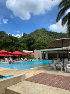 a swimming pool with chairs and umbrellas and a mountain at Hotel Rossé in La Vega