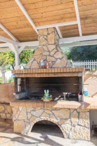 a stone fireplace in a patio with a wooden roof at Pipetos house in Acharavi