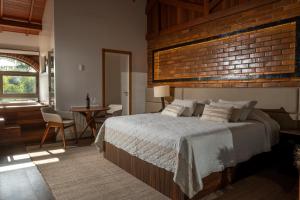 a bedroom with a large bed and a brick wall at Casa Valduga Pousada Boutique in Bento Gonçalves