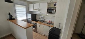 a kitchen with white cabinets and a washer and dryer at Appart Papy in LʼUnion