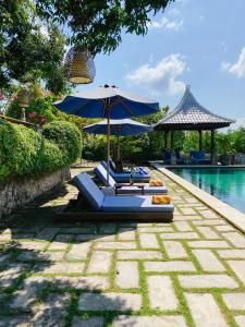 two lounge chairs and an umbrella next to a pool at Villa Olala Penida in Toyapakeh