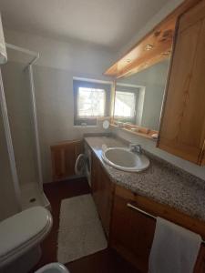 a bathroom with a sink and a toilet and a mirror at Bormio and Livigno house in Isolaccia