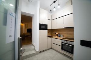 a kitchen with white cabinets and a door leading to a living room at Ema Apartments in Satu Mare