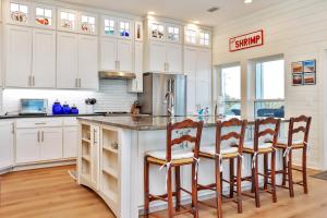 a kitchen with white cabinets and a large island with bar stools at Sea Forever by Pristine Properties Vacation Rentals in Indian Pass