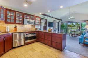 a large kitchen with wooden cabinets and stainless steel appliances at Waipouli Beach Resort E301 in Kapaa