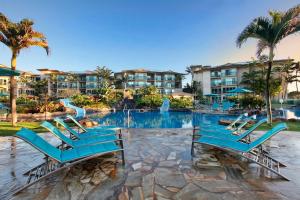 a pool at a resort with blue chairs and a slide at Waipouli Beach Resort E301 in Kapaa