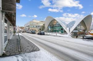 a snow covered street with a building and a road at Stille leilighet med topp beliggenhet i Tromsø sentrum in Tromsø