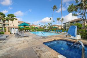 a swimming pool with lounge chairs and a swimming pool at Pono Kai F207 in Kapaa