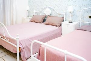 two beds in a bedroom with pink and white at PEPEROSA Rooms and Events - Peaceful countryside escape with pool, private parking, just minutes from the sea, Anzio and Nettuno in Nettuno