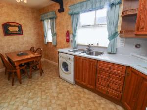 a kitchen with a sink and a washing machine at Honeysuckle in Wooler