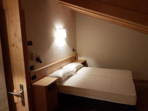 Un dormitorio con una cama con una luz en la pared. en Casa De Sandre, en San Vito di Cadore