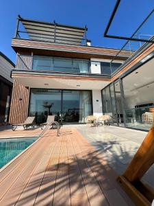 a house with a wooden deck and a swimming pool at 5-Bedroom Villa with Pool & Sauna in Dosemealti