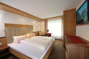 a bedroom with a large bed and a flat screen tv at Jungmann Apartments in Ischgl