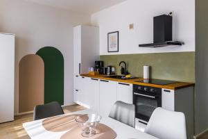 a kitchen with white cabinets and a table with chairs at Design ElbOase-Zentral-Parkplatz-Waschmaschine-2 separate Schlafplätze in Pirna