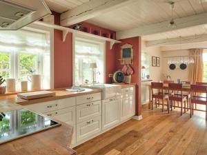 cocina con armarios blancos y comedor en holiday home with 3 bedrooms, en Wrixum