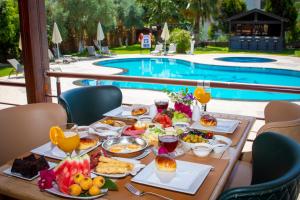 a table with breakfast foods and drinks next to a swimming pool at Mesken Inn Göcek Hotel in Göcek