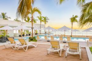 a resort with a pool and chairs and palm trees at Harbor NT2505 by Moikkarentals in Puerto Vallarta