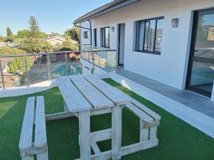 a wooden bench sitting on the grass in front of a house at Foundation Stones Lodge Summerstrand in Gqeberha