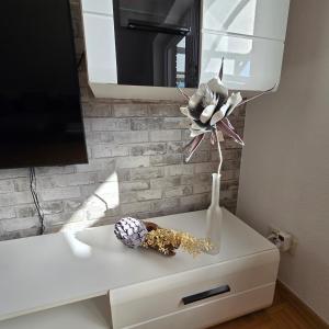 ein weißer Schrank mit einer Vase mit einer Blume darauf in der Unterkunft Große Dachgeschosswohnung in Löhne-Bad Oeynhausen in Löhne