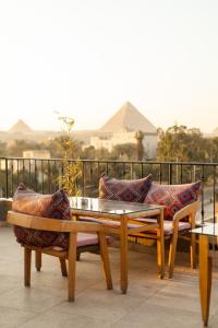 2 panche e un tavolo con cuscini sul balcone di Almas Pyramids View Hotel a Il Cairo
