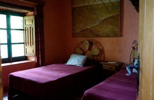 two beds in a room with purple sheets at Cortijo Rural Finca HUERTA SANTA MARÍA in Galaroza