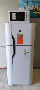 a white refrigerator with a microwave on top of it at Monoambiente Coqueto in Venado Tuerto